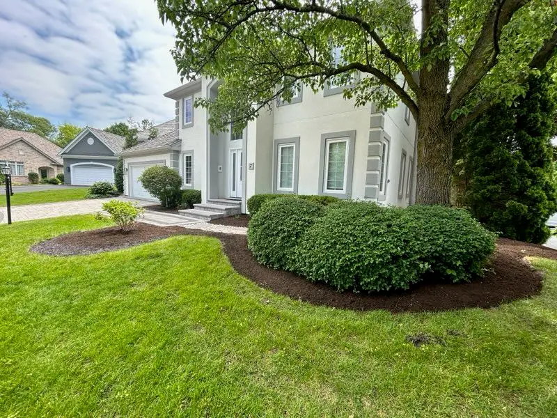 Freshly weeded landscape beds with neatly trimmed shrubs and fresh mulch at a residential property in Barrington, IL.